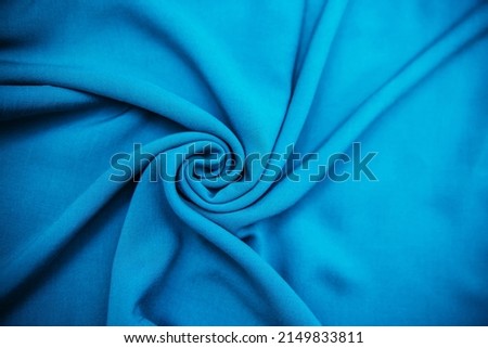 Blue wrinkled fabric lies in folds on the table with drapery.Texture