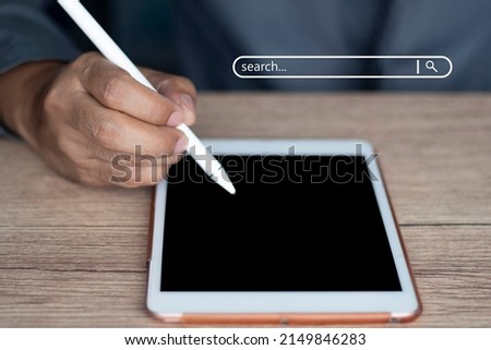 A businessman takes a digital tablet and holds down the stylus on the virtual screen of the search bar button. internet information (Focus on hand)