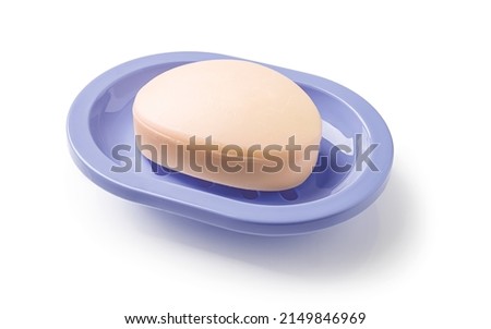 Soap on a soap dish isolated on a white background. Oval shaped beige soap bar in a violet blue plastic soapbox for bathroom and shower. Washing hands, toiletries and purity concepts. Top view. Royalty-Free Stock Photo #2149846969