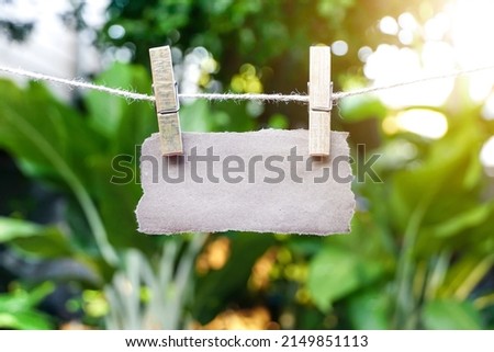 empty Brown paper torn or ripped pieces hanged with clothes pegs on rope at the green garden.   