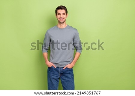 Photo of funny young brunet guy wear grey pullover jeans isolated on green color background
