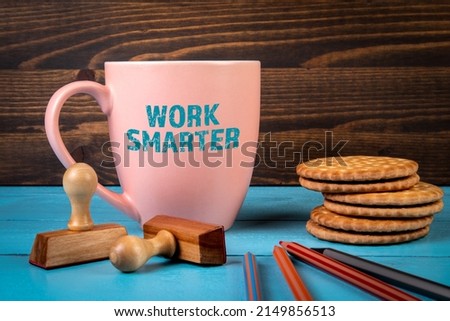 Work Smarter. Coffee mug with text on a blue office desk.