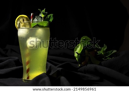 Fresh Homemade Lemonade or mojito cocktail with lemon, mint and ice on dark bacground