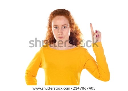 Young pretty woman smiling confidently pointing to something, positive, relaxed, satisfied attitude against white background