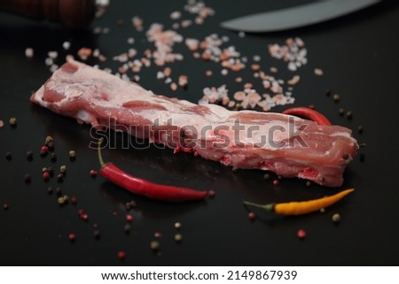 subject photography of a piece of fresh pork meat on a subject table with thawed peppers and decorative salt