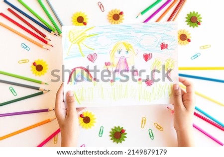 A child draws a postcard for mother's day. Beautiful landscape with mom drawn with pencils. Happy mother's day. Happy birthday card for mom