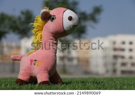 A Giraffe doll on the green grass, with Front Outdoor lighting and Urban background.