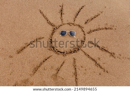 the sun is painted on the sand. sunglasses.
