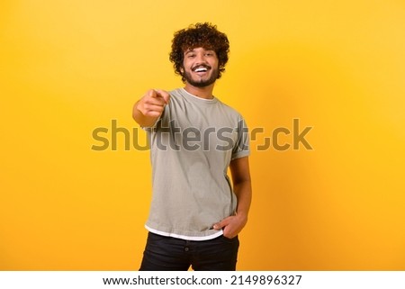 Smiling young indian man with curly hairstyle pointing finger at you standing isolated on yellow background, cheerful teenage guy indicating at the camera Royalty-Free Stock Photo #2149896327