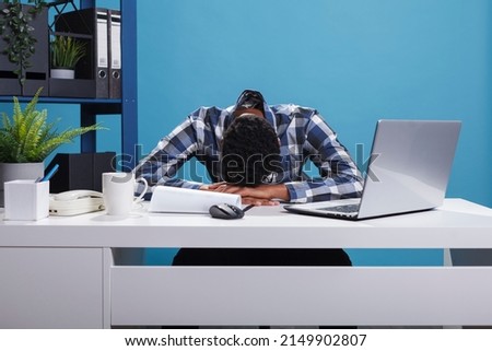 Exhausted and tired young adult office worker falling asleep on desk because of overtime work hours. Burnout fatigued company employee being sleepy and stressed because of huge work effort. Royalty-Free Stock Photo #2149902807