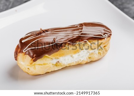 Eclair with chocolate on a white plate. Traditional french eclairs with chocolate. Tasty colorful dessert profiteroles. chocolate eclair, Traditional french dessert eclair with custard and chocolate.  Royalty-Free Stock Photo #2149917365