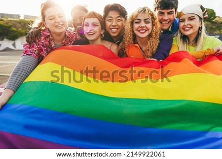 Young diverse people having fun holding LGBT rainbow flag outdoor - Focus on center blond girl Royalty-Free Stock Photo #2149922061