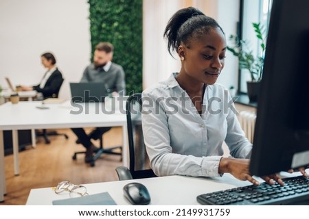 Young african american woman developer working on a laptop computer in a creative office environment. Project manager is developing data and scheduling a project.