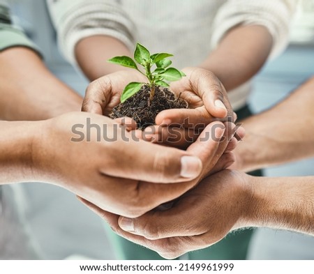 Help and well grow together. Cropped shot of a group of people holding a plant growing out of soil. Royalty-Free Stock Photo #2149961999