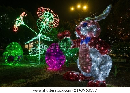 Bunny made of tinsel and garlands in the dark of the night. Easter symbol. Urban scenery during the celebration. Background with copy space