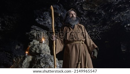 Elderly sorcerer standing inside cave Royalty-Free Stock Photo #2149965547