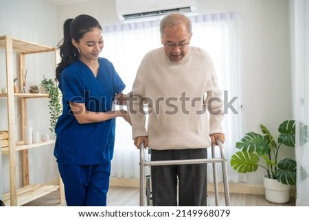 Asian senior elderly man patient doing physical therapy with caregiver. Attractive specialist carer women help and support older mature male practice walking slowly with walker at nursing home care. Royalty-Free Stock Photo #2149968079
