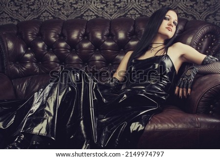 Gothic girl in dark dress lays on divan Royalty-Free Stock Photo #2149974797