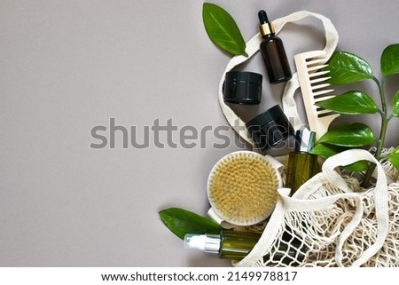 Set of Eco friendly beauty products. Natural brush, bottles with pipettes, jars cream skincare for body and face in mesh bag with green leaves on beige background. Copy space,Flat lay. Eco shop banner