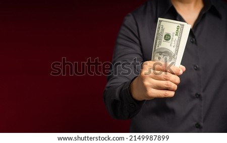 Business and finance concept. Businessman holding US banknotes on a red background while standing in the studio. Personal loans and payday loans. Space for text
