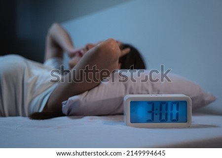 woman have insomnia on the bed selective focus on alarm clock at three in the morning. Royalty-Free Stock Photo #2149994645