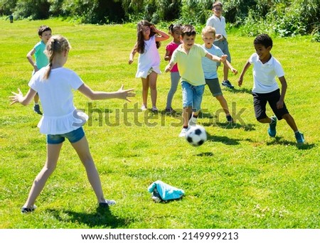 Cheerful children are jogning with ball on the playground. High quality photo