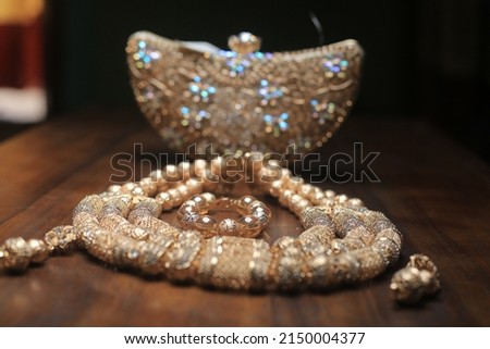 golden bag and necklace, the picture is showing a capture of golden bag and necklace.