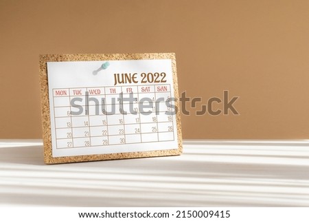 Calendar sheet for 2022. Desktop calendar for month of June, attached to cork board with a button on desktop. Concept of event planning, reminders. Royalty-Free Stock Photo #2150009415