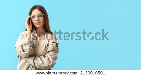 Pretty young woman wearing eyeglasses on light blue background with space for text Royalty-Free Stock Photo #2150010501