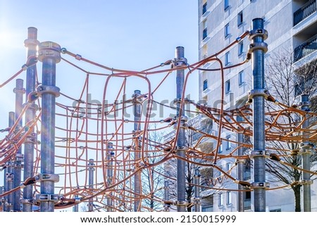 climbing ropes of a playground in front of a modern concrete plattenbau facade - photo