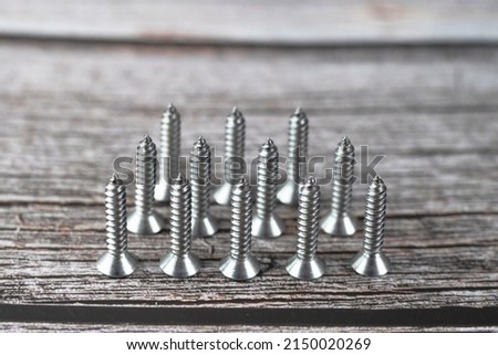 Tapping screws made of steel on wood background, metal screw, iron screw, chrome screw, screws as a background, wood screw, concept industry. copy space for text. Royalty-Free Stock Photo #2150020269