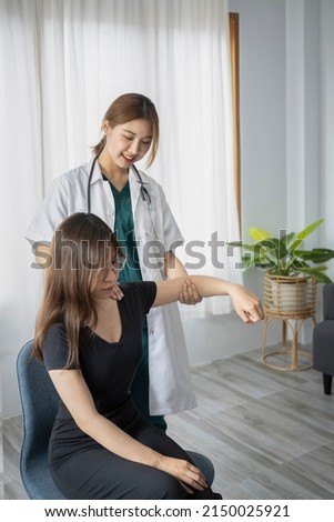 Female physiotherapist working examining treating injured arm of  female patient in clinic.