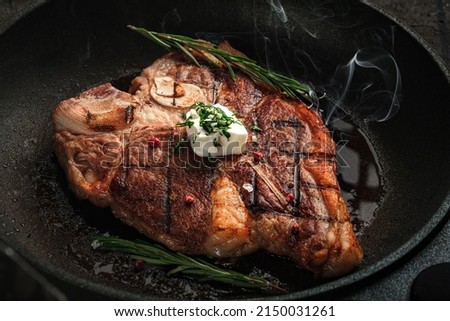 T-bone steak steaming in a grill pan with spices, rosemary and butter. Premium Porterhouse steak on the bone Royalty-Free Stock Photo #2150031261