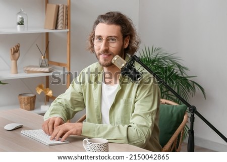 Male blogger using computer and microphone at home