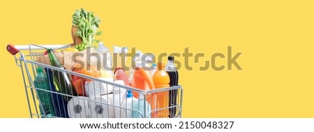 Shopping cart filled with fresh goods on yellow background, grocery shopping banner, blank copy space