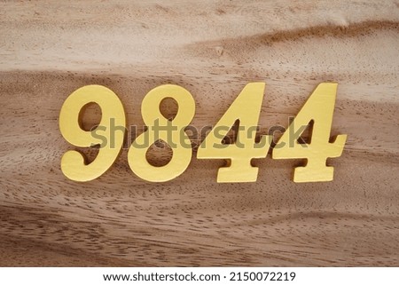 Wooden  numerals 9844 painted in gold on a dark brown and white patterned plank background.