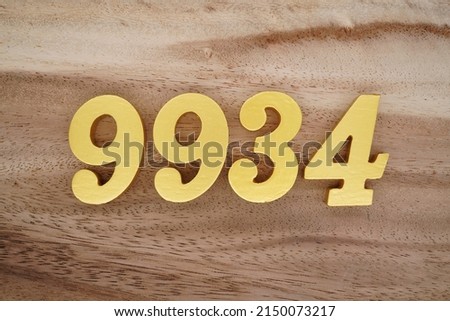 Wooden  numerals 9934 painted in gold on a dark brown and white patterned plank background.