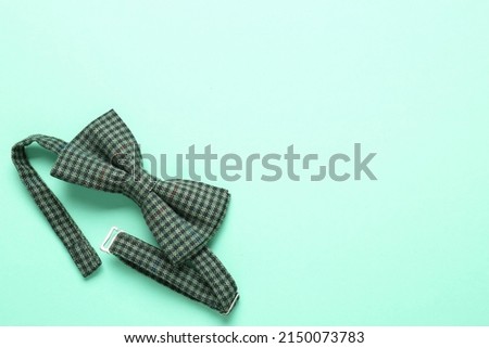 Stylish gingham bow tie on light green background, top view. Space for text