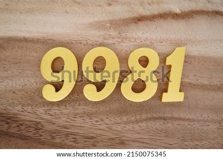 Wooden  numerals 9981 painted in gold on a dark brown and white patterned plank background.