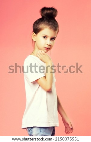 Portrait of beautiful brunette little girl looking at camera. Fashion photo over pink background
