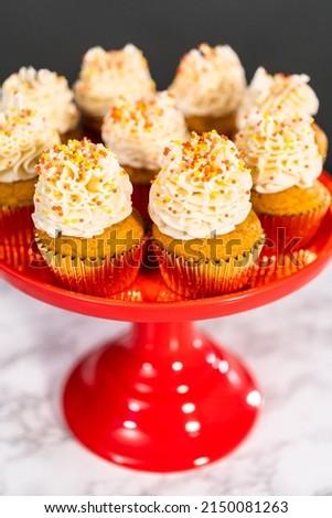 Pumpkin spice cupcake with Italian buttercream and sprinkles on a cake stand.
