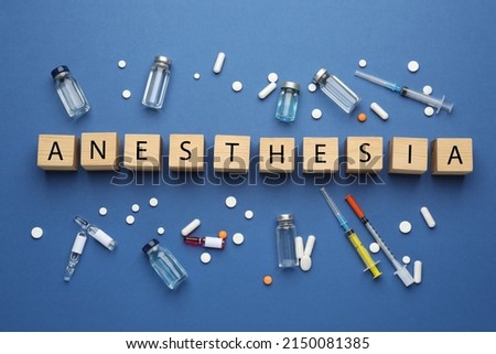 Word Anesthesia made of wooden cubes and drugs on blue background, flat lay Royalty-Free Stock Photo #2150081385