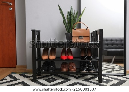 Shelving unit with stylish shoes and large mirror near grey wall in hallway Royalty-Free Stock Photo #2150081507