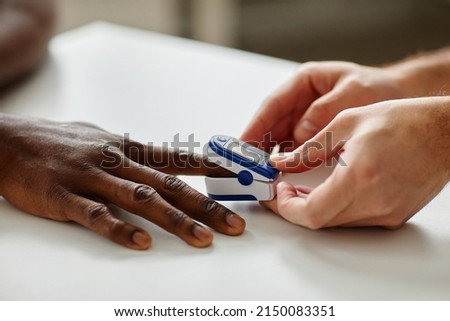 Close-up shot of unrecognizable doctor applying pulse oximeter on Black patients finger during appointment Royalty-Free Stock Photo #2150083351