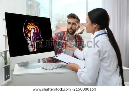 Neurologist showing brain scan to patient in clinic Royalty-Free Stock Photo #2150088153