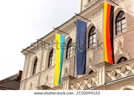 Flags of Ukraine, Germany and European Union side by side in front of a historic building