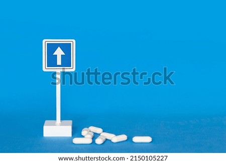 up arrow sign and white pills on blue background