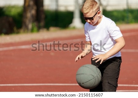 caucasian boy blond plays with a basketball ball on the sports ground. High quality photo