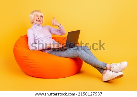 Full size profile side photo of cheerful woman use laptop show thumb-up advertise approve isolated over yellow color background