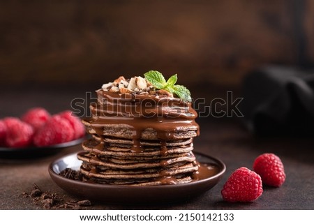 Stack of chocolate pancakes with sauce and raspberries Royalty-Free Stock Photo #2150142133